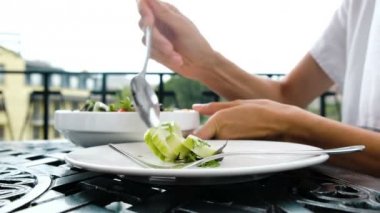 Kadın bir sebze salata salatalık ve domates bir tabak içinde koyar.