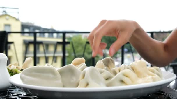 Vrouw neemt en eet plantaardig dumplings over de plaat met haar handen — Stockvideo