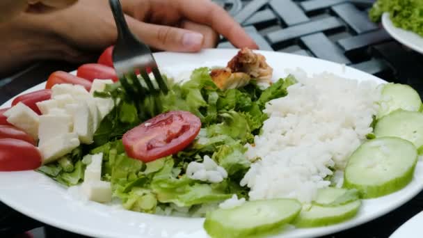 Девушка расхаживает на вилке овощной салат в тарелке с рисом и кебабом крупным планом — стоковое видео