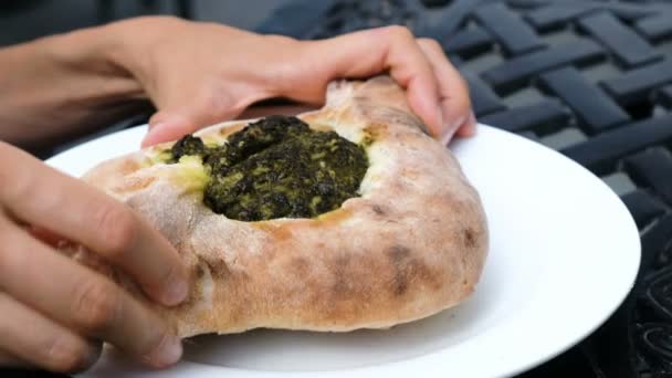 Mujer rompe un pedazo de pan khachapuri y mezcla relleno de espinacas, cocina nacional georgiana — Vídeos de Stock