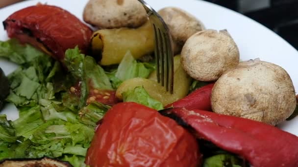 Женщина ест овощи на гриле с вилкой, замедленная съемка — стоковое видео
