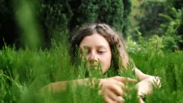 Jovem mulher encaracolada mostrando amor à natureza e ao meio ambiente, abraçando uma planta — Vídeo de Stock