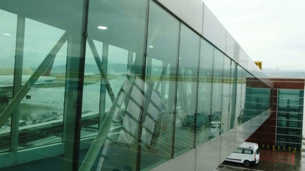 Menschen gehen an einem transparenten Fußgängerüberweg im Terminal entlang, um in das Flugzeug zu steigen — Stockvideo
