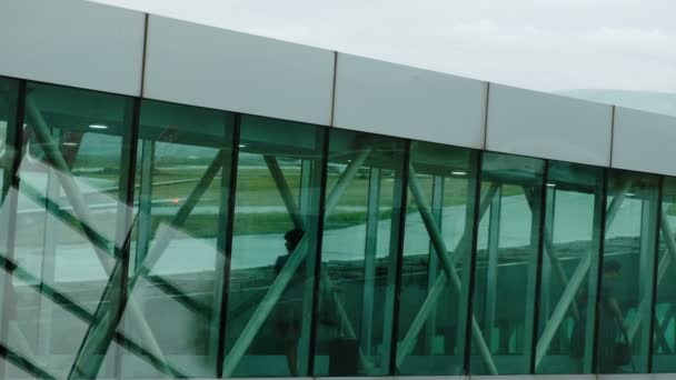 Tourists goes on a telescopic ramp, silhouettes of passengers pass along the corridor — Stock Video