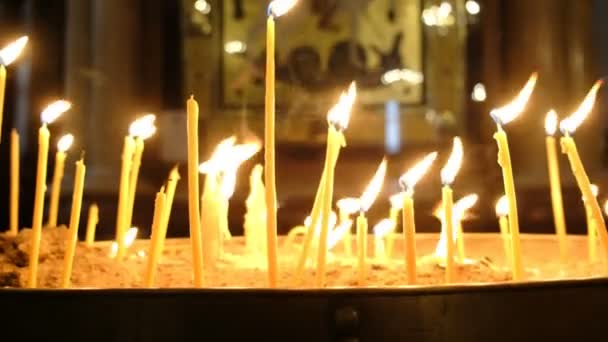 Candele di cera bruciano al buio nella Chiesa ortodossa incorniciata da un'antica icona — Video Stock