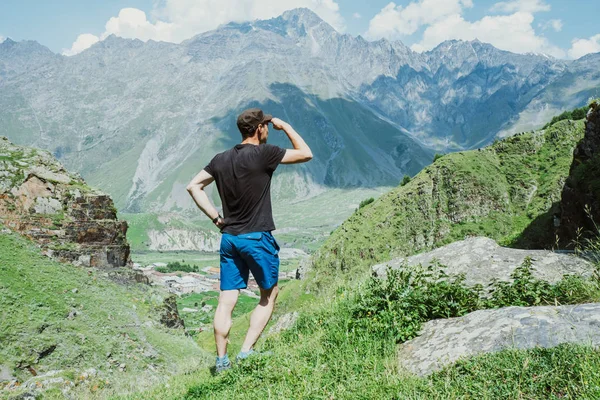 Homem fica na colina e olhando para uma montanha — Fotografia de Stock