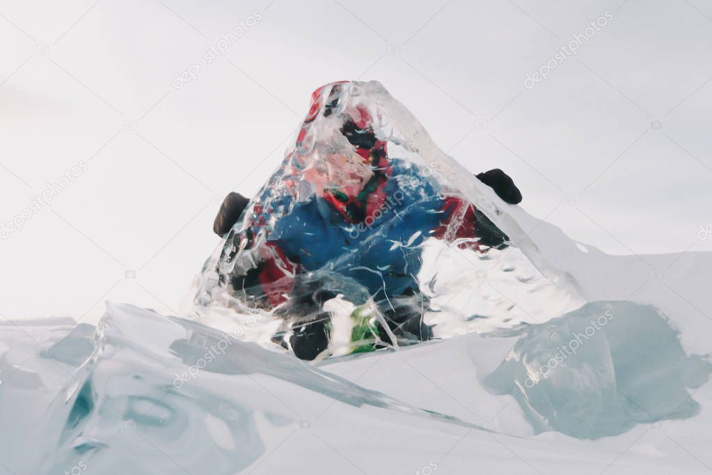 A man looks through a transparent ice on Lake Baikal