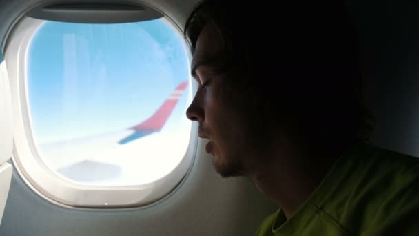 ひげを持つ男が、飛行中に飛行機の窓近く眠っています。 — ストック動画