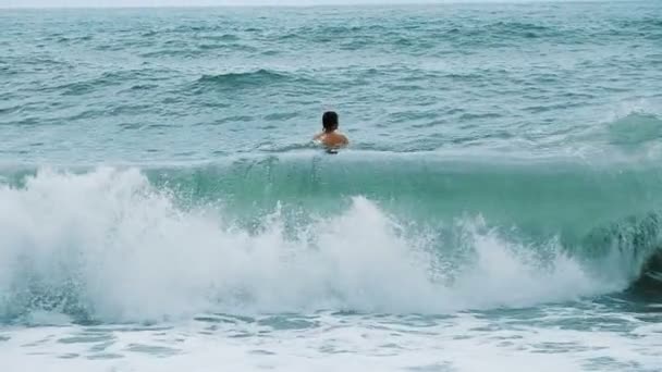 Чоловік плаває в морі в штормі, гойдається на хвилях, повільний рух — стокове відео