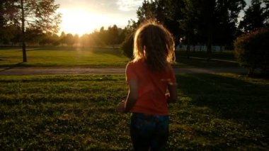 Süper ağır çekim - güneş ışığı zemin karşı çimenlerin üzerinde bir kadın koşu