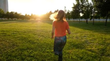 Spor kadınla çimenlerin üzerinde sunset Bulvarında bir şehir parkı, yavaş koşu yapıyor