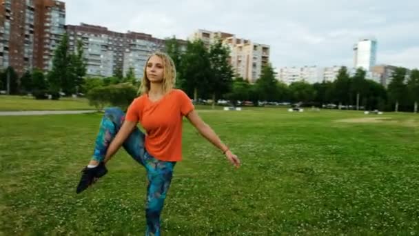 Ginasta levanta uma perna em um fio vertical em um parque da cidade, movimento da câmera — Vídeo de Stock