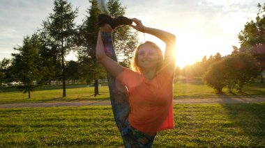 Jimnastikçi günbatımı, kamera hareketi bir şehir Park'ta dikey bir sicim içinde bir bacak asansörleri