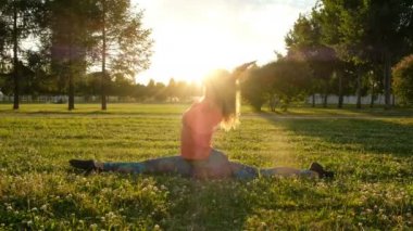 Jimnastikçi kadın boyuna üzerinde oturur ve enine böler. Şehir Parkı germe