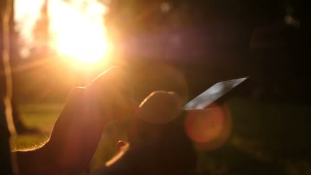 Az ember használ smartphone. Ember kézzel mozgatható lövés közelről naplemente. Pihenjen, természet koncepció. — Stock videók