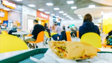Hızlandırılmış kafe, ısırıldı sandviç yeme bulanık ziyaretçi arka planı masada yatıyor