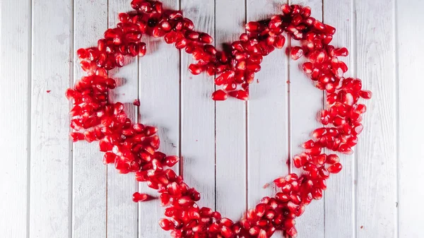 Stop motion on pomegranate seeds is peeled in the shape of a heart, randomly on the table