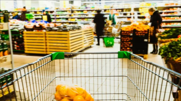 Poklatkowy prędkości wózka na zakupy jeździ do supermarketu i pełne żywności, regały i niewyraźne kupujących — Zdjęcie stockowe