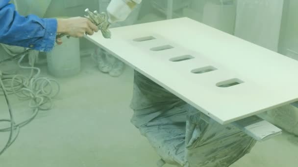 Працівник фарбує фанерний лист на меблевій фабриці. Виготовлення дерев'яних меблів — стокове відео