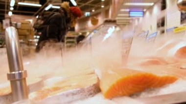 Kırmızı balık biftek buz bir süpermarket ekran durumda nadas yalan. Arka planda alıcıların ürünleri seçin..