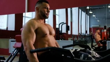 Vücut geliştirmeci trenler bacaklar, orta planı. Adam ile Halter makine fitness merkezinde egzersiz yaparak.