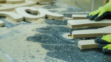 İşçi, bir mobilya fabrikasında pah yarıçapı kesiciyi kaldırır, yakın çekim. Ahşap mobilya imalatı