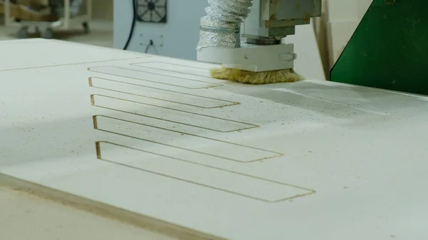 Moderna macchina per la lavorazione del legno in azione. Tagli pezzi ricci da foglio di compensato. Produzione di mobili in legno — Foto Stock