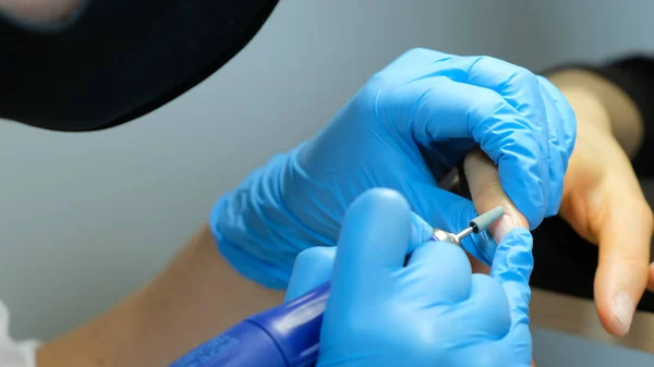 Manicure, nagel kunstenaar verwerkt nagels met manicure frees cutter. Dienst van de schoonheid, nagel salon, gezondheidszorg en cosmetica. Close-up — Stockfoto