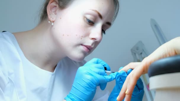 Manicurista aplica esmalte de uñas. Cuidado de uñas en un salón de belleza. Mujer haciéndose manicura de uñas, tratamientos de spa . — Vídeos de Stock