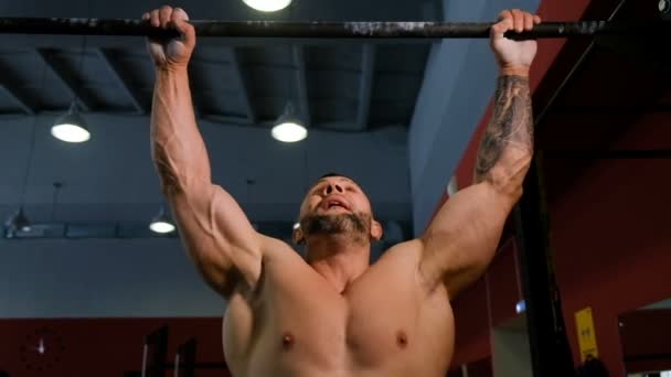 Brutal musculoso hombre se detuvo en la barra en el gimnasio de cámara lenta — Vídeos de Stock