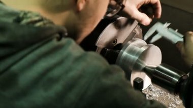 Turner bir kumpas ile metal İşlenecek parçanın boyutlarını ölçer. Bir Torna üzerinde çalışmak
