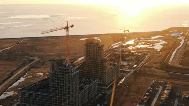 Вид з повітря на будівельний майданчик з будівельними кранами на заході сонця — стокове відео