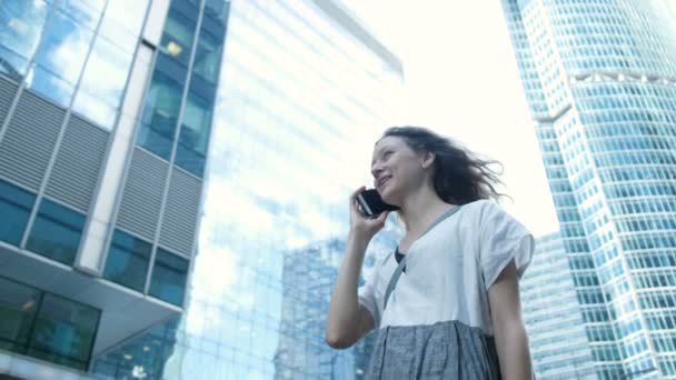 Gadis bisnis dalam gaun berbicara di telepon di latar belakang pencakar langit — Stok Video