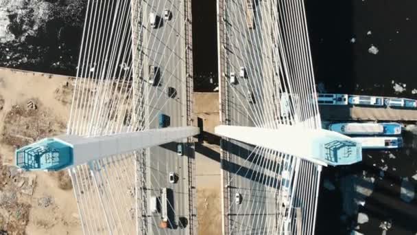 Над канатным мостом над рекой стоят грузовики и автомобили, вид с воздуха — стоковое видео