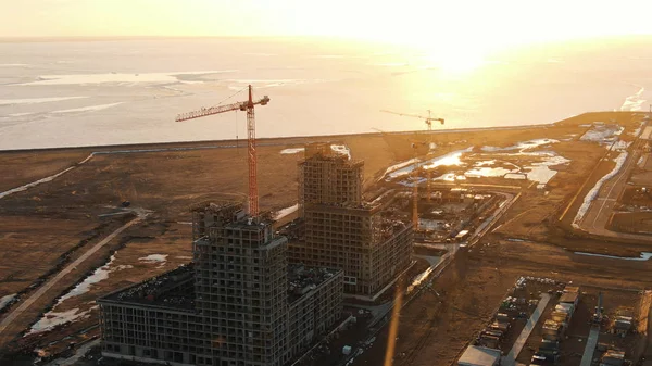 Widok z lotu ptaka budowy z dźwigów budowlanych o zachodzie słońca — Zdjęcie stockowe