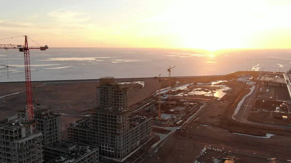 Flying over construction sites on the sea at sunset, aerial shot