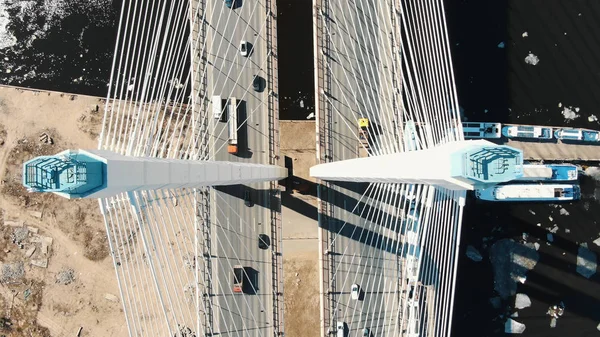 Over cable-stayed bridge over the river are trucks and cars, aerial view