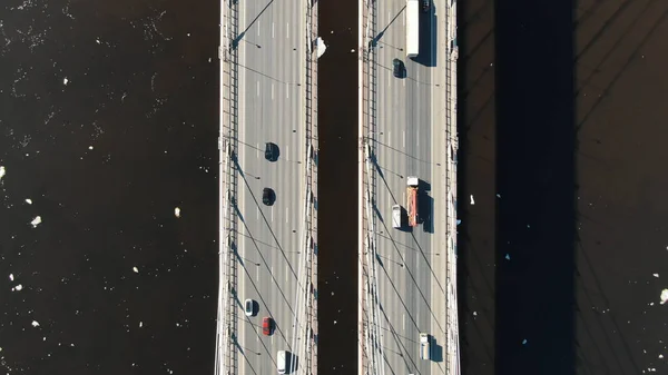 Flusso di auto cavalca attraverso un ponte funivia attraverso il fiume, sparando da un drone — Foto Stock