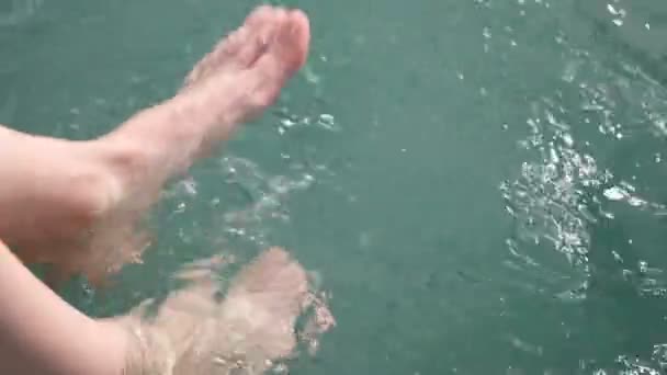 Mujer salpicando y jugando con los pies en el mar — Vídeo de stock