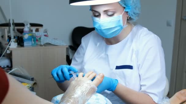 Master of pedicure saws the nail plate on the legs and prepares the nails for gel polish. Home beauty salon — Stock Video