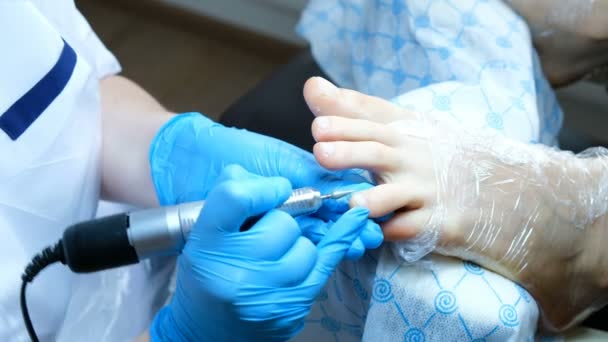 Pedikyrtekniker avlägsnar nagelbanden och behandlar huden nära nageln — Stockvideo