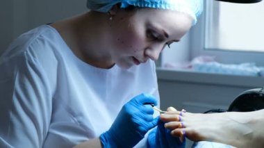 Pedikür ustası dikkatle çivi jel cila uygular