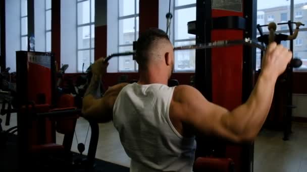 Caballero construye los músculos de la espalda sentado en la máquina de fitness — Vídeo de stock