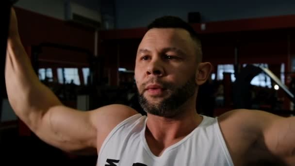 Handsome guy with big biceps trains arm and chest muscles — Stock Video
