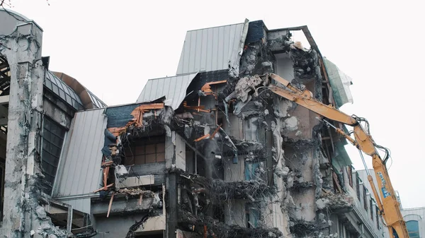 Vernietiging van het huis met een bulldozer. Ontmanteling van het oude gebouw. Graafmachine vernietigt de muren van een verlaten huis — Stockfoto