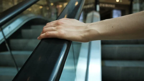 Girls hand on escalator handrail in mall, close-up