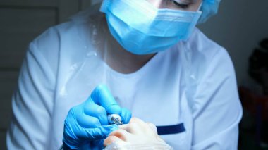 güzellik ustası ayak ayak tutar ve makine ile pedikür yapar