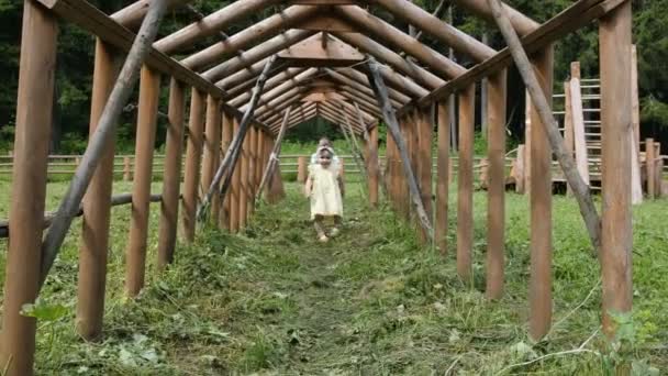 Jeune dame gaie court sous la construction de poutres en bois — Video