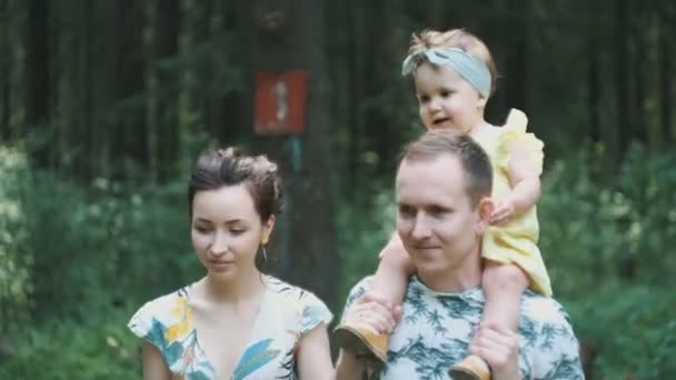 Handsome man holds daughter on shoulders wandering in forest — Stock Video