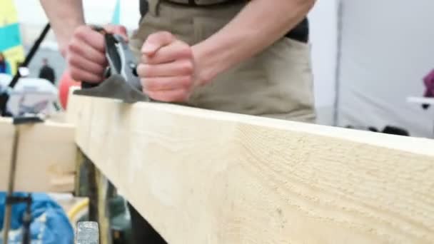 Carpenter in green jumpsuit carves brown wooden board — Stock Video